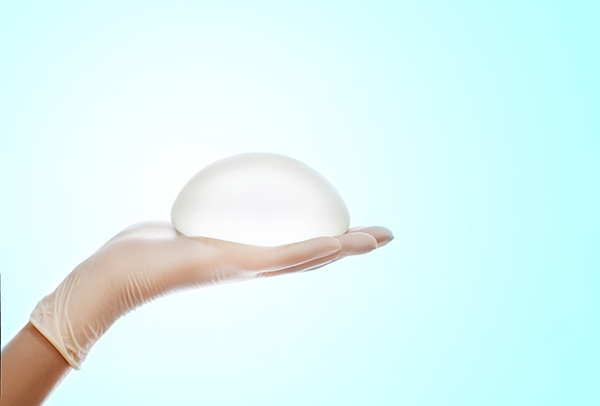 Plastic surgeon holds breast implant to discuss revision surgery 