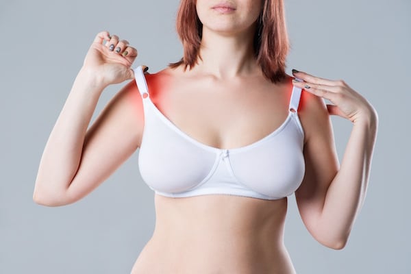 Woman with irritated skin under bra, irritation on the body from underwear on gray background