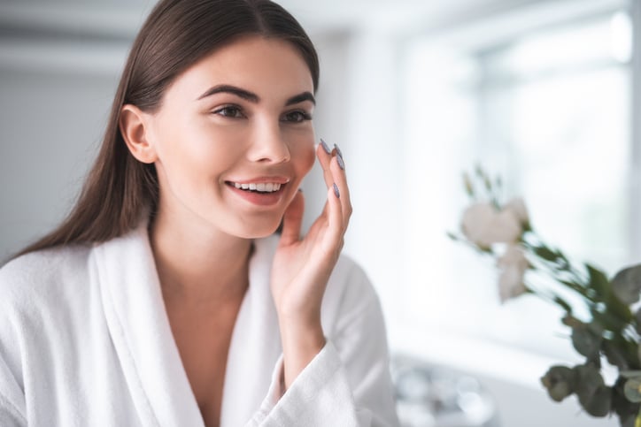 Satisfied girl doing face treatment in morning