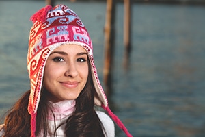 Pretty young woman in winter clothing along the bay at sunset