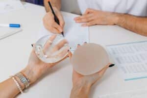 Woman holding two different types of implants in a consultation with a plastic surgeon.