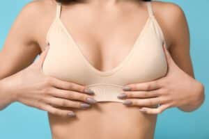 Woman in bra with holding her breasts after breast implant removal