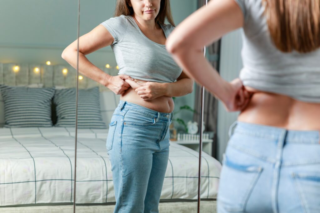 Woman looking at her abdomen in a mirror